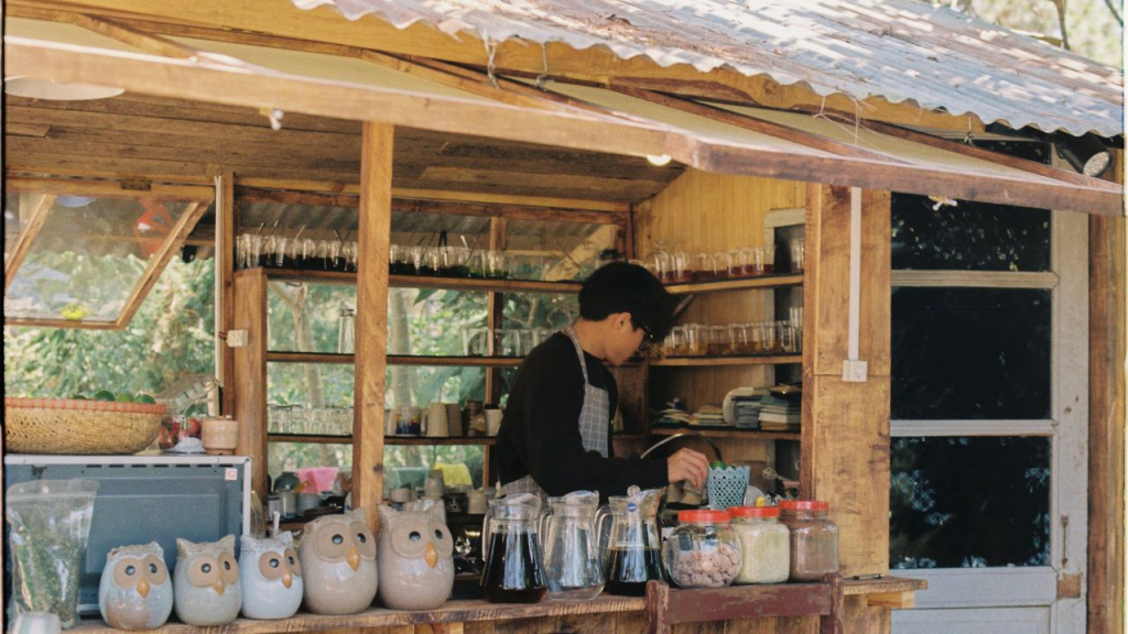 Barista working inside a rustic wooden bubble tea shop.