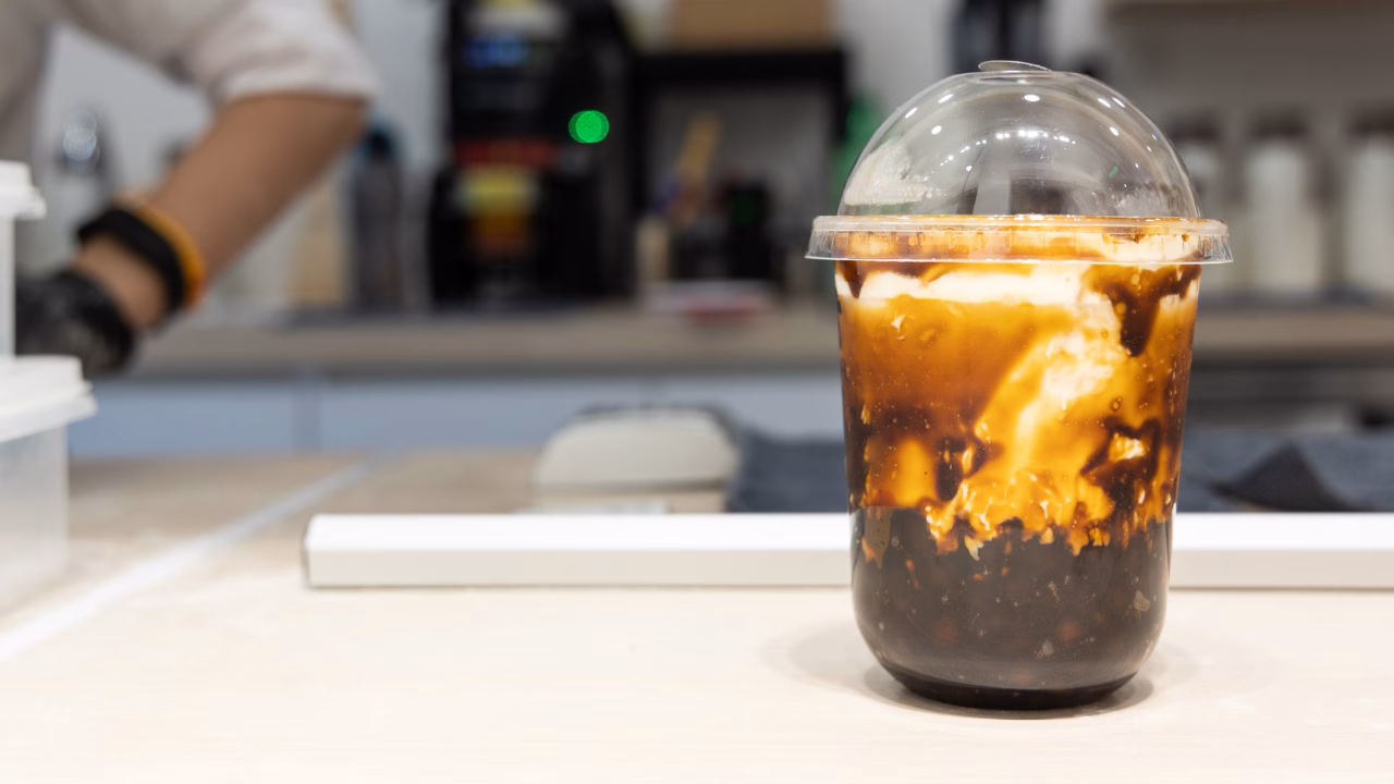 Brown sugar bubble tea with milk in a clear plastic cup.