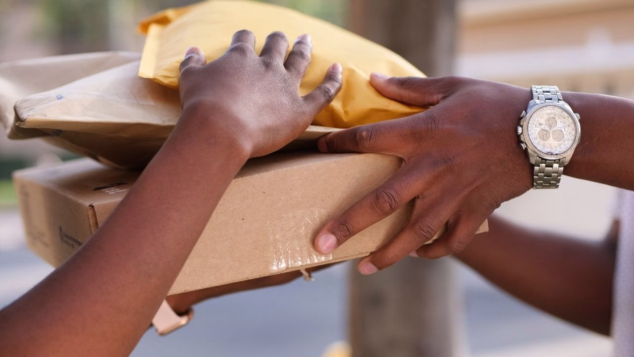 Close-up of hands exchanging cardboard boxes and envelopes.