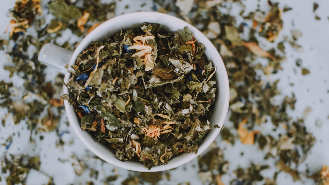 White cup filled with loose herbal tea leaves and petals.