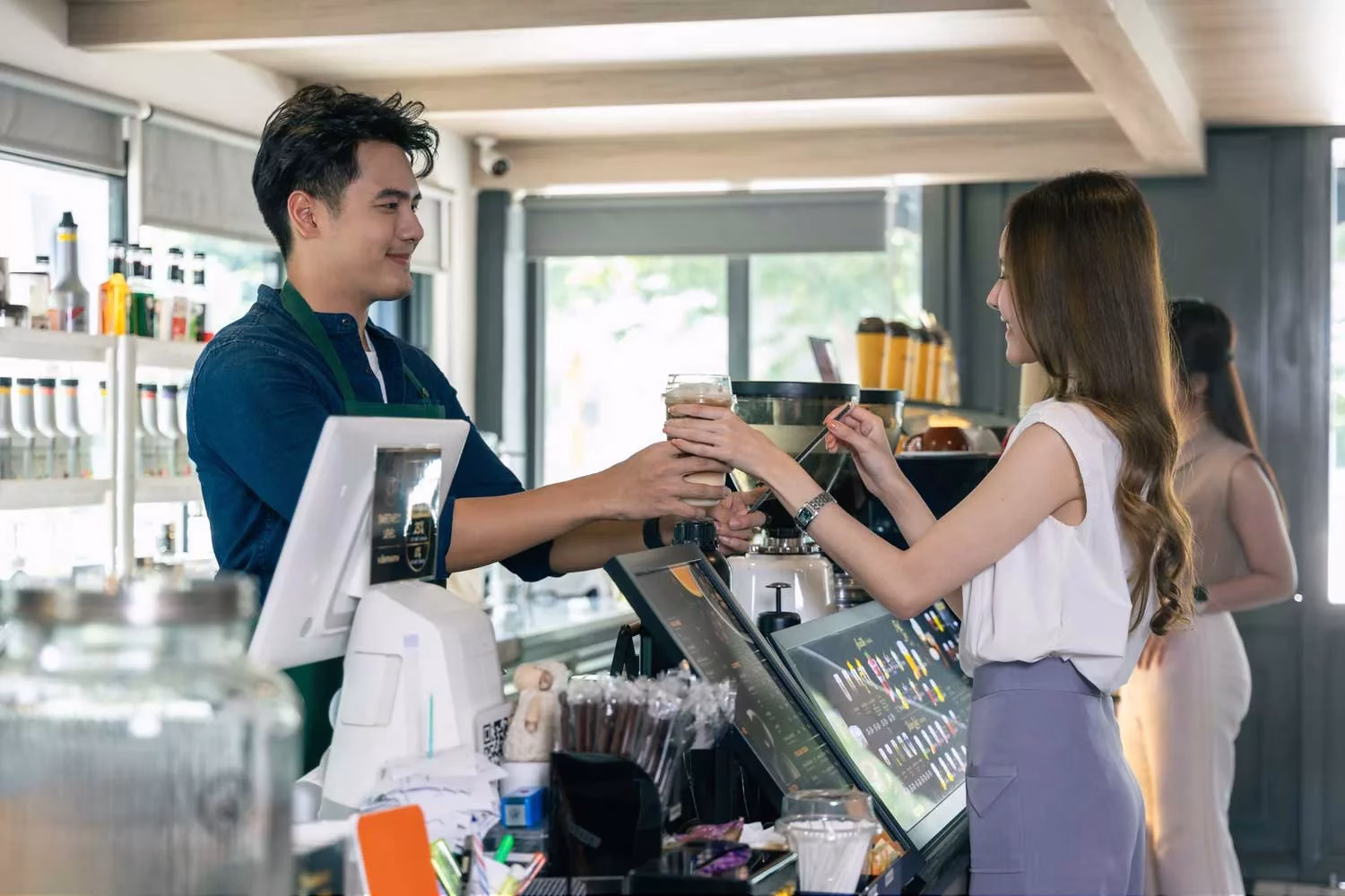Smiling Asian Barista Proudly Serving Coffee in Coffee Shop