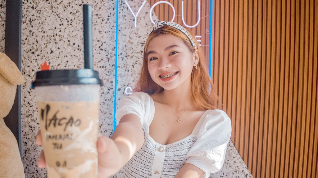 Smiling girl holding bubble tea in cafe.