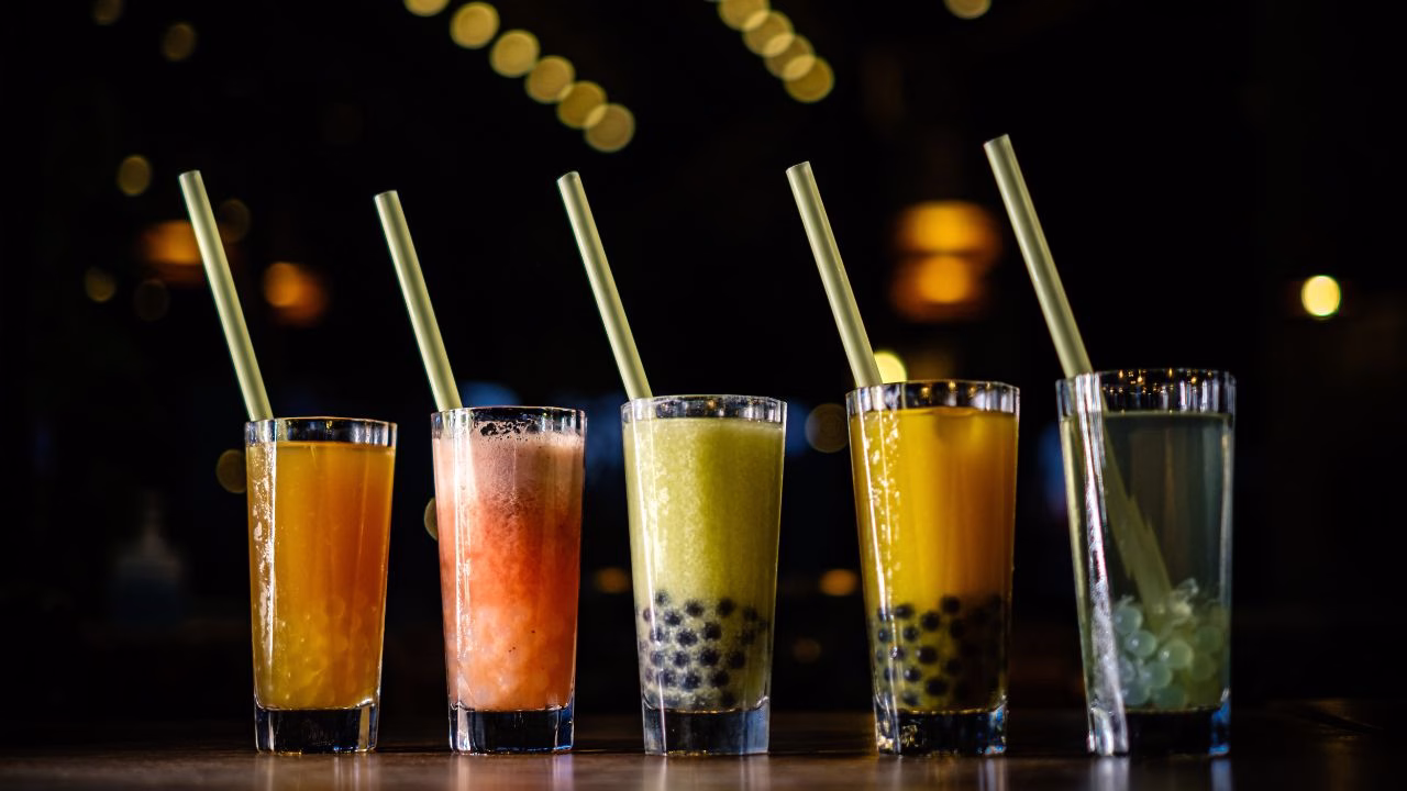 Five colourful bubble tea drinks in a row.